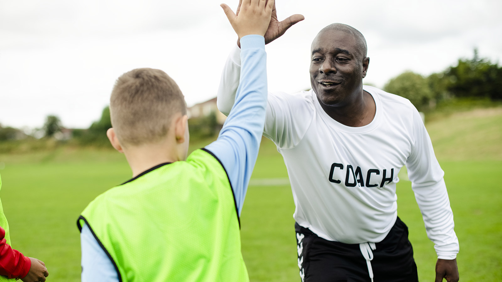 Coach Dan high-fiving a soccer player